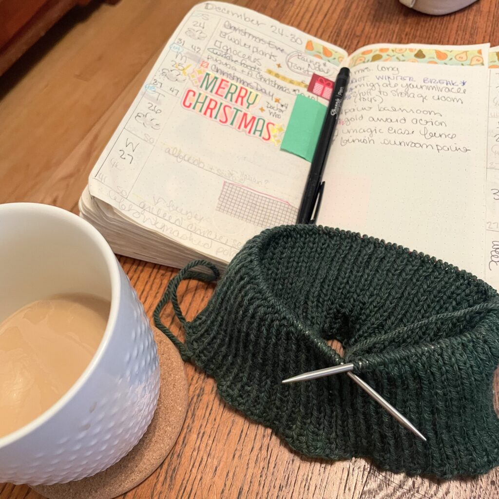about three inches of green 1x1 ribbing on a circular needle. my book is in the background. my coffee cup (half full) is in the forground.